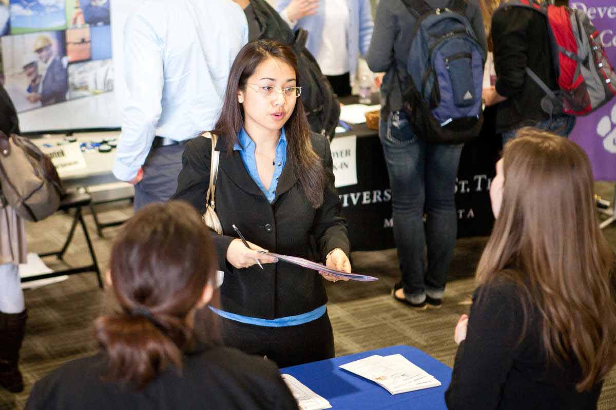 A student speaks to a recruiter at a job fair.